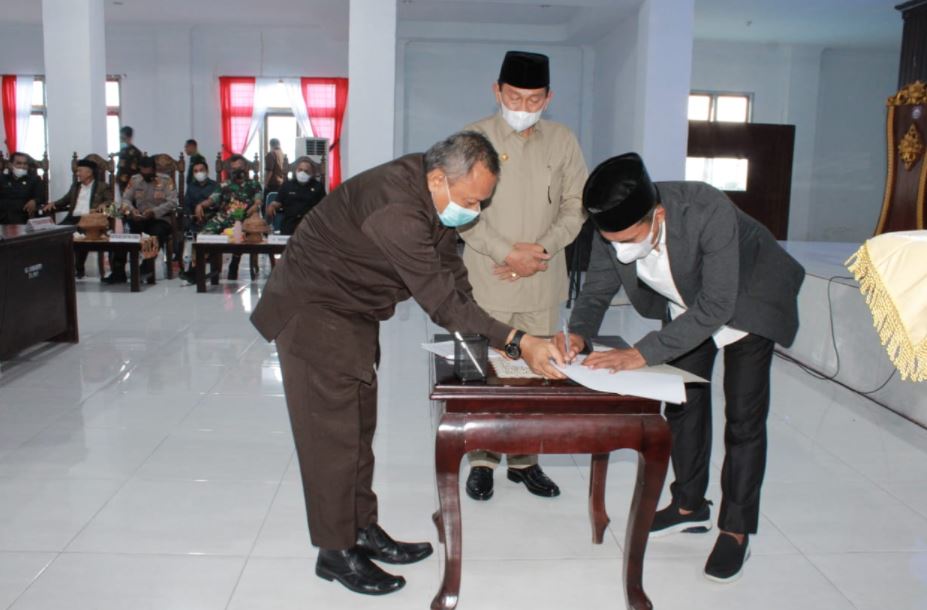 Ketua DPRD Butur, Diwan, S.Pd saat menandatangani nota kesepakatan bersama Bupati Buton Utara, Dr. Muh. Ridwan Zakariah, M.Si terkait persetujuan 11 peraturan daerah