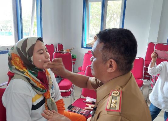 Kepala Dinas Pemuda dan Olahraga Mubar, Alimran memakaikan bedak diwajah istrinya dalam acara lomba suami merias wajah istri. Foto: Akhirman