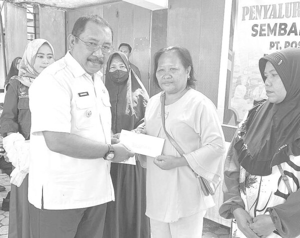 Pj Bupati Bombana Burhanuddin menyerahkan bantuan tunai kepada warga prasejahtera di pelataran Kantor Pos Bombana, kemairn.